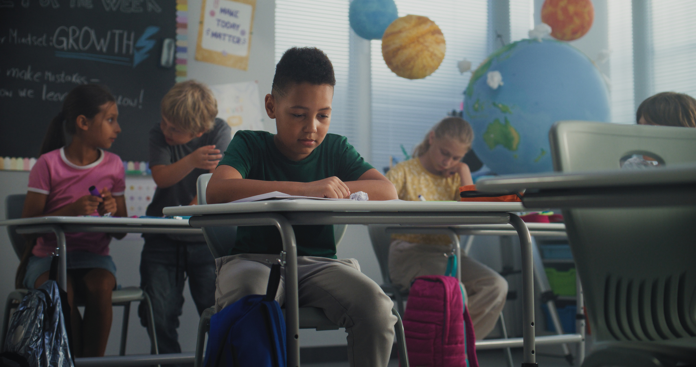Stressed Primary School Boy Sitting at Desk While Classmates Abusing and Bullying Him growing pains